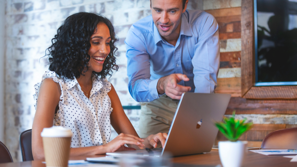 Woman smiling at laptop with coworker
